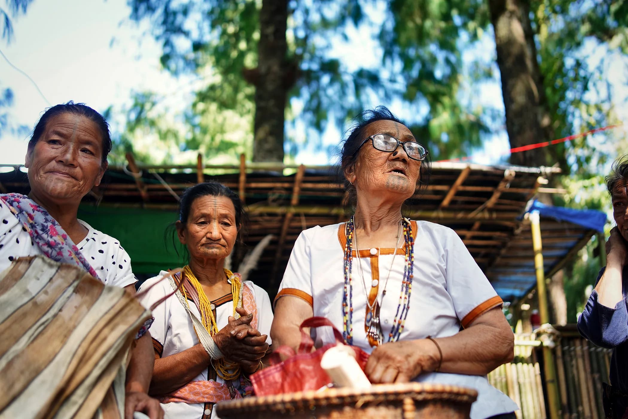 Three elder women in traditional dress and beadwork at the festival ground