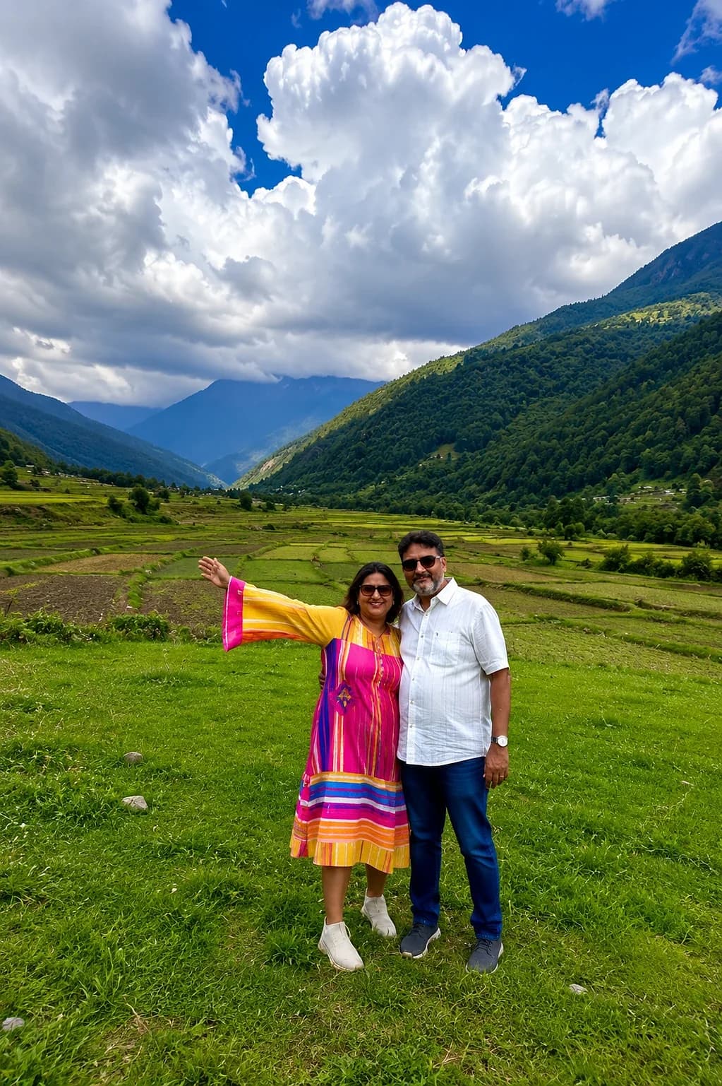 A couple standing in terraced fields under monsoon cloud, forested hills behind