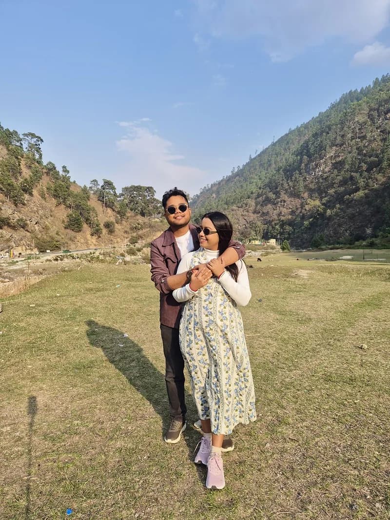 A couple on the grassy floor of a river valley, pine ridges rising on both sides