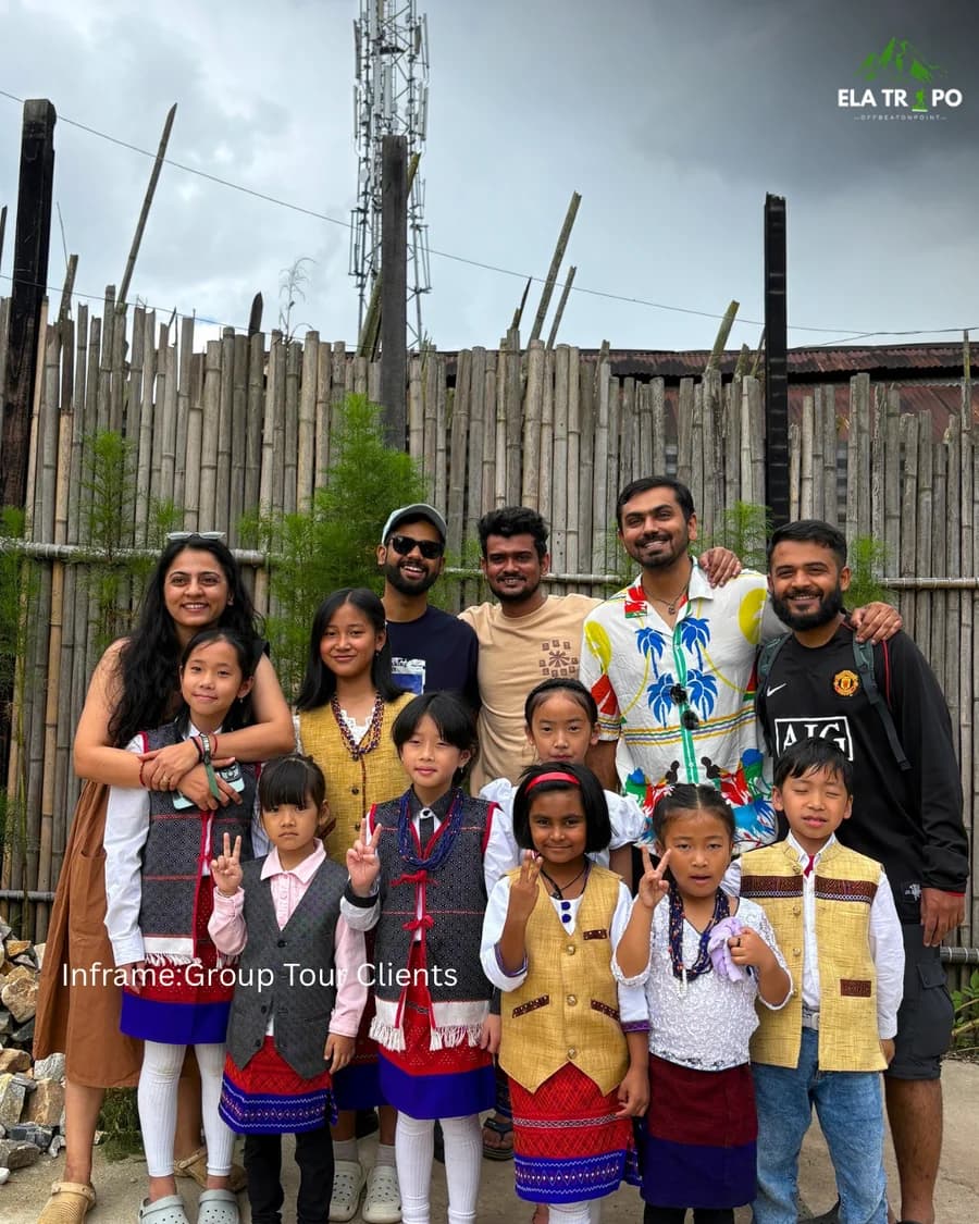 Travellers with a group of village children in traditional Apatani dress, bamboo fence behind them