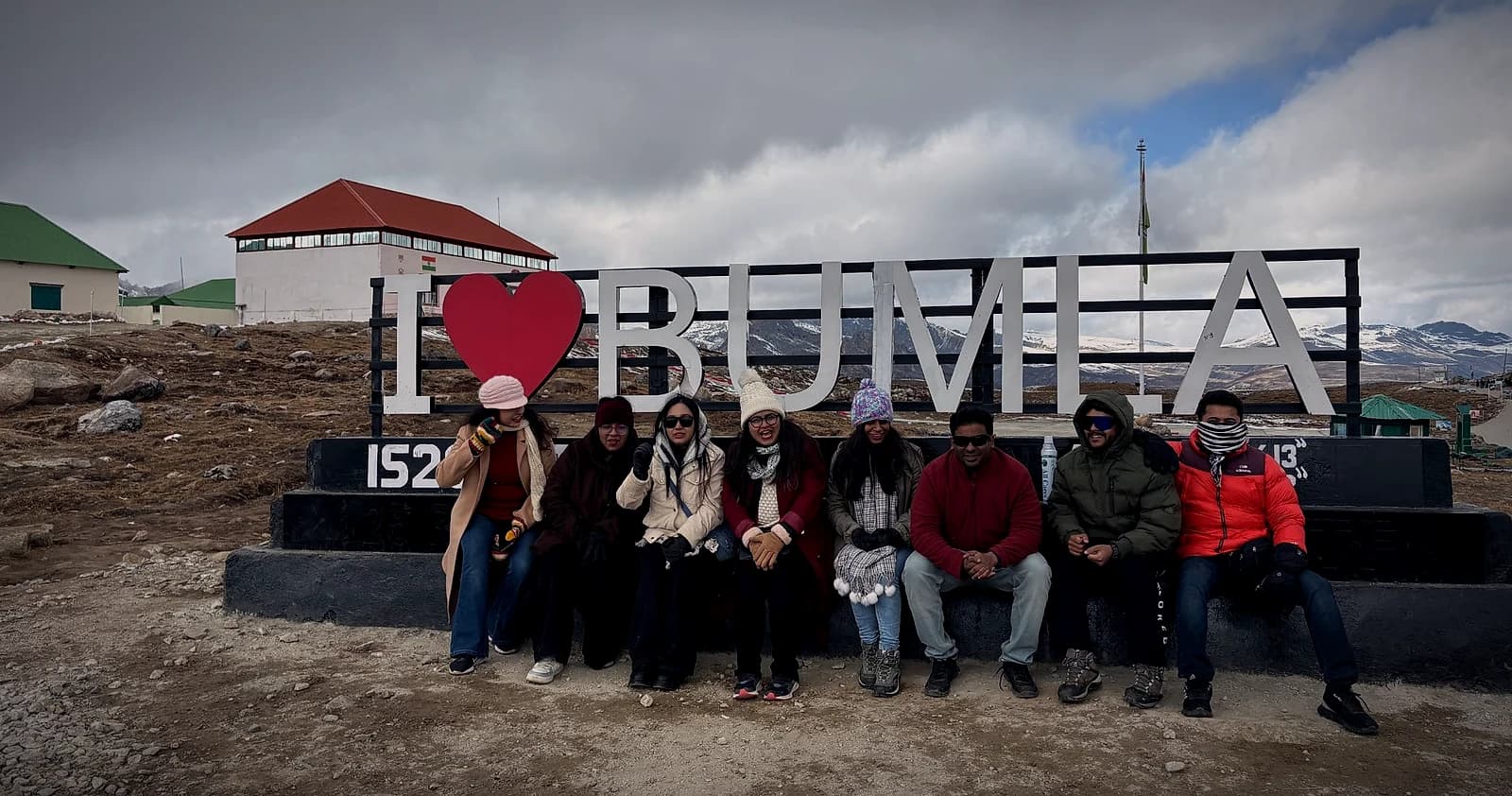 A group seated along the I ♥ Bumla sign on the India–China border