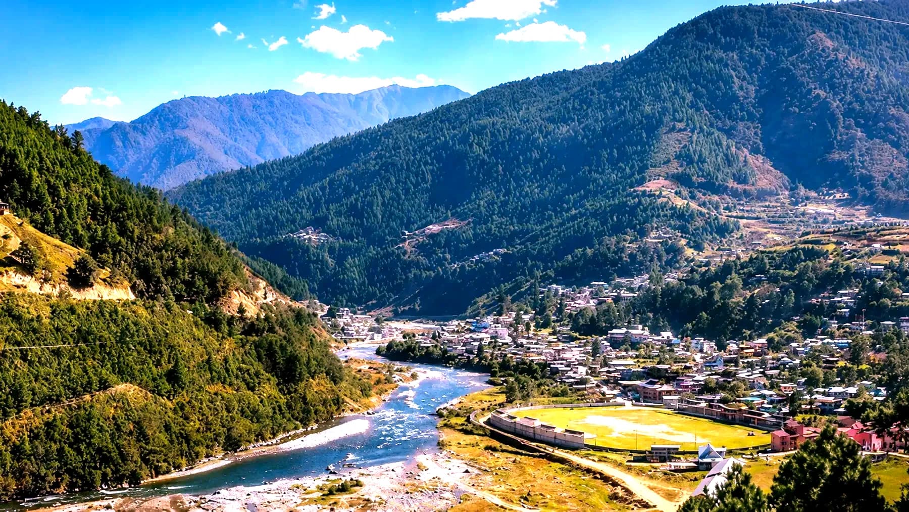 The Dirang valley with a river running through it, the town spread along the far bank below forested ridges