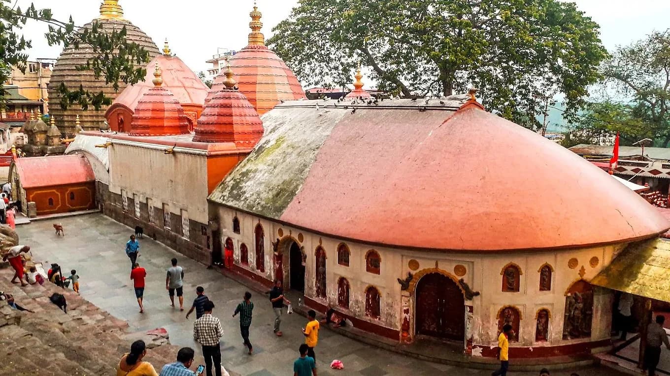 The red domes and courtyard of the Kamakhya temple in Guwahati, with people crossing the flagstones
