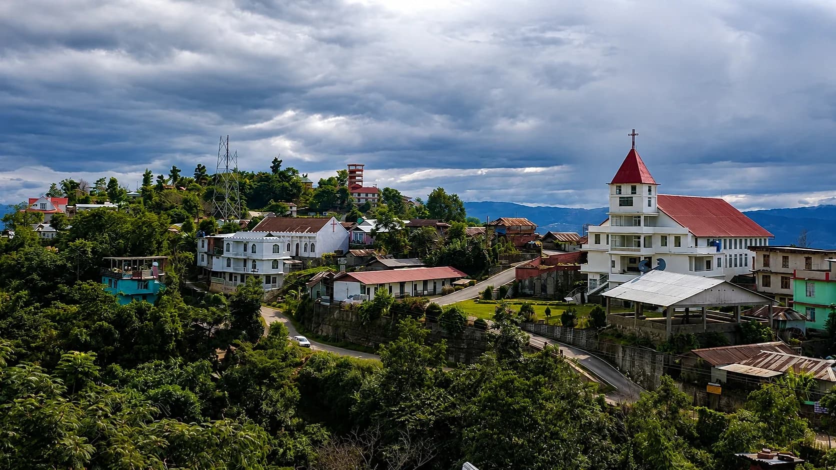 The village at Tuophema along its ridge, a red-roofed church standing above the houses under heavy cloud