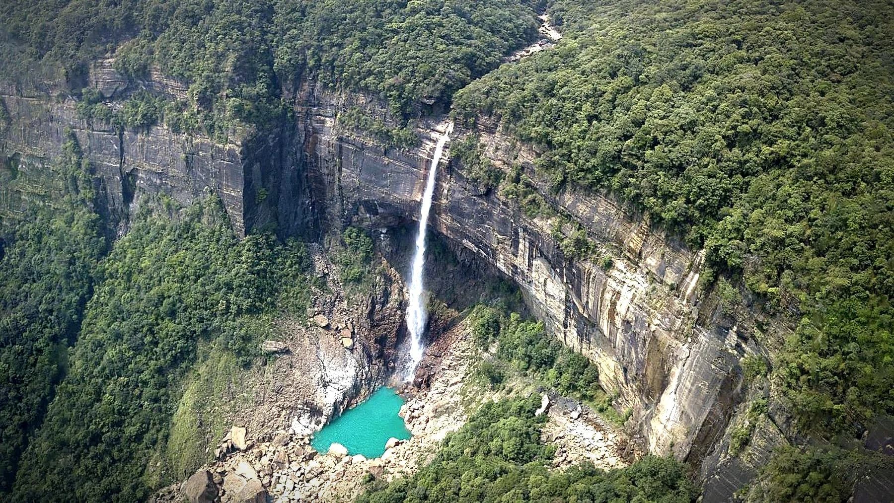 Nohkalikai Falls dropping into a turquoise plunge pool below forested cliffs, Meghalaya