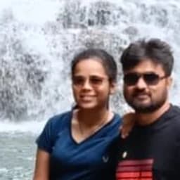 Ashwini and Pushkar below a tiered waterfall in Meghalaya