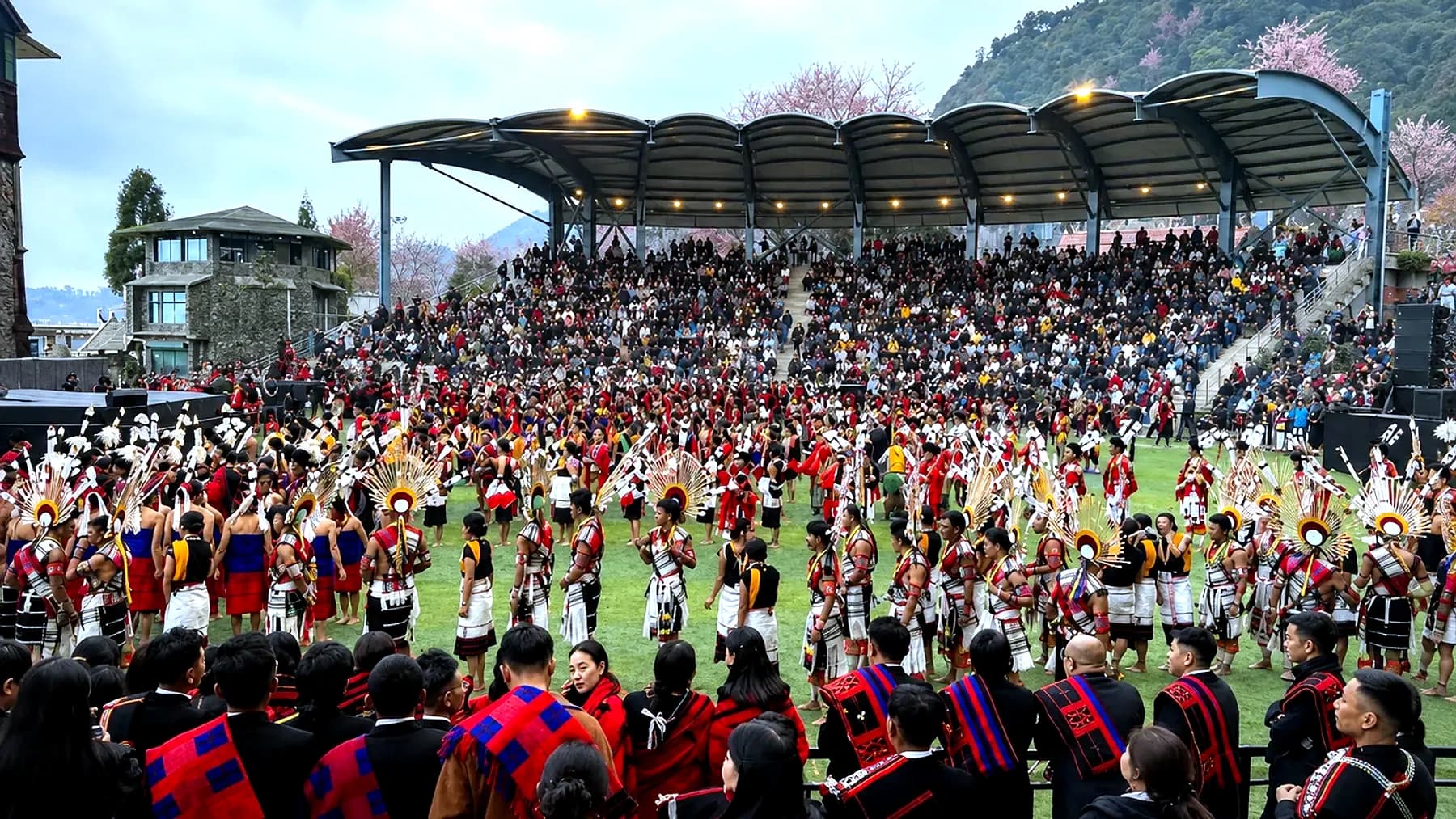 Naga dancers in feathered headdress filling the arena at Kisama, with the terraced crowd behind